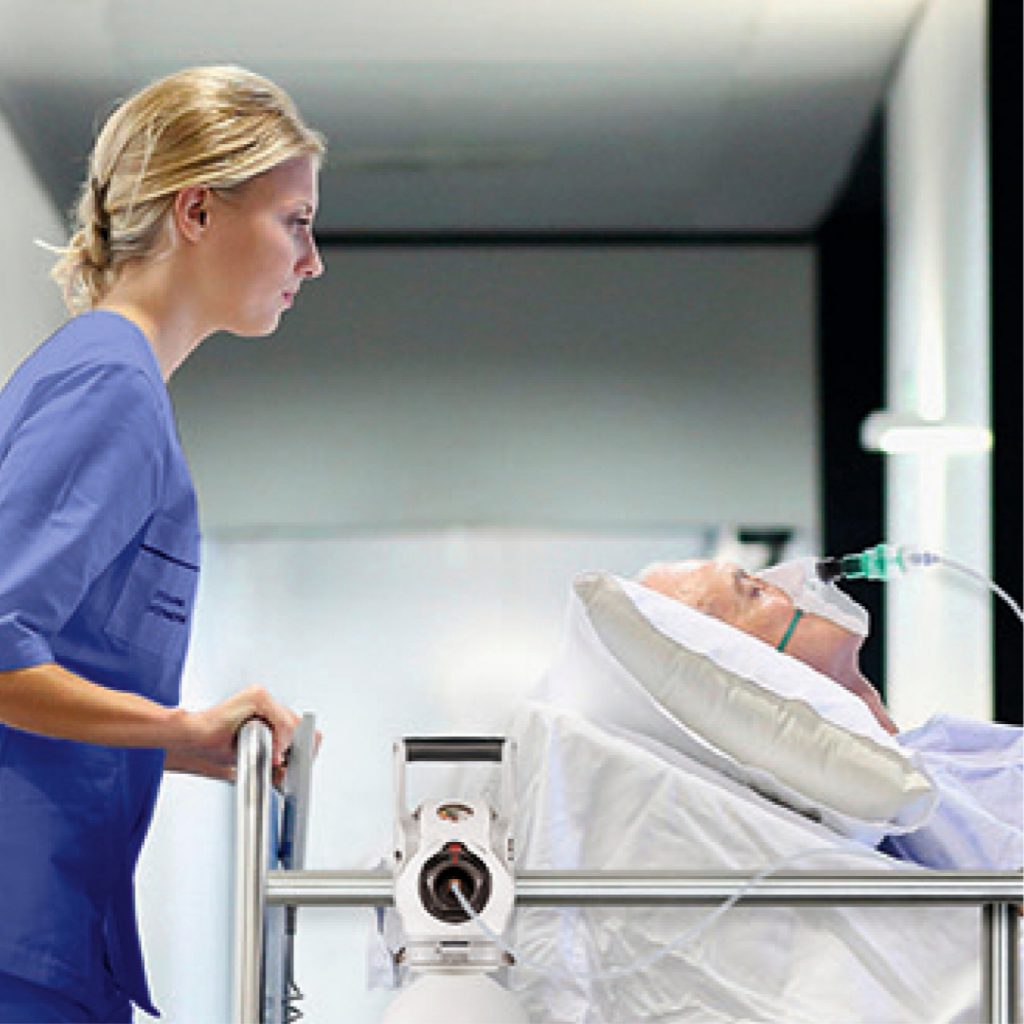 ICU・ERの場合は院内移動時に流量調整器付き酸素ボンベをベッドにかけて患者運ぶ看護師。